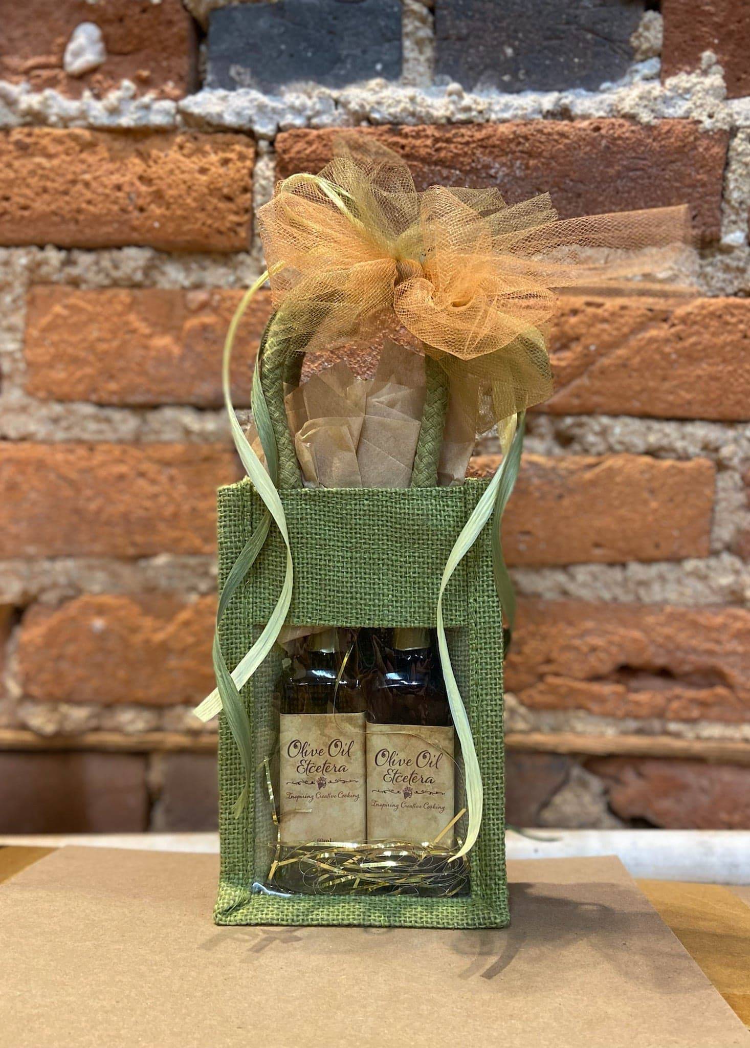 Green burlap gift bag with 2 60 ml bottles of oil and vinegar